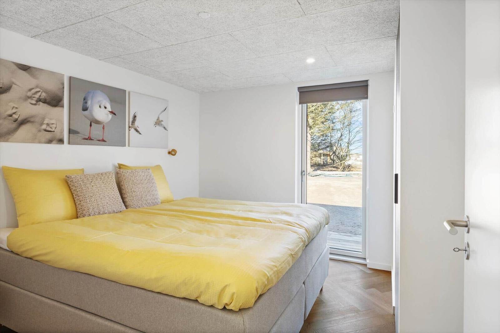 Schlafzimmer mit Bett, Wandbildern und Fenster zur Außenseite.