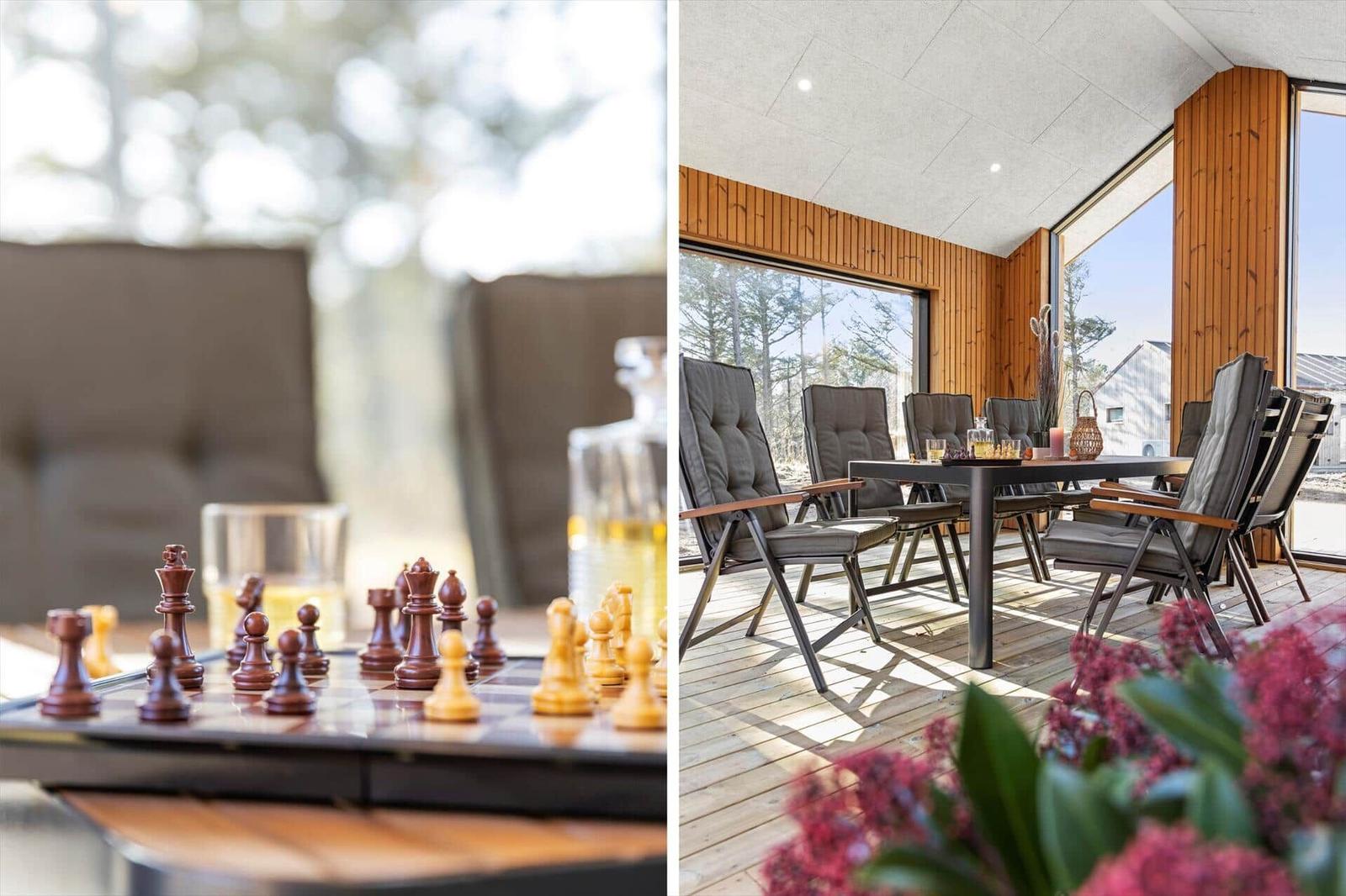 Schachspiel auf Tisch mit Getränken. Holzterrasse mit Sitzgruppe und Blick auf Wald.