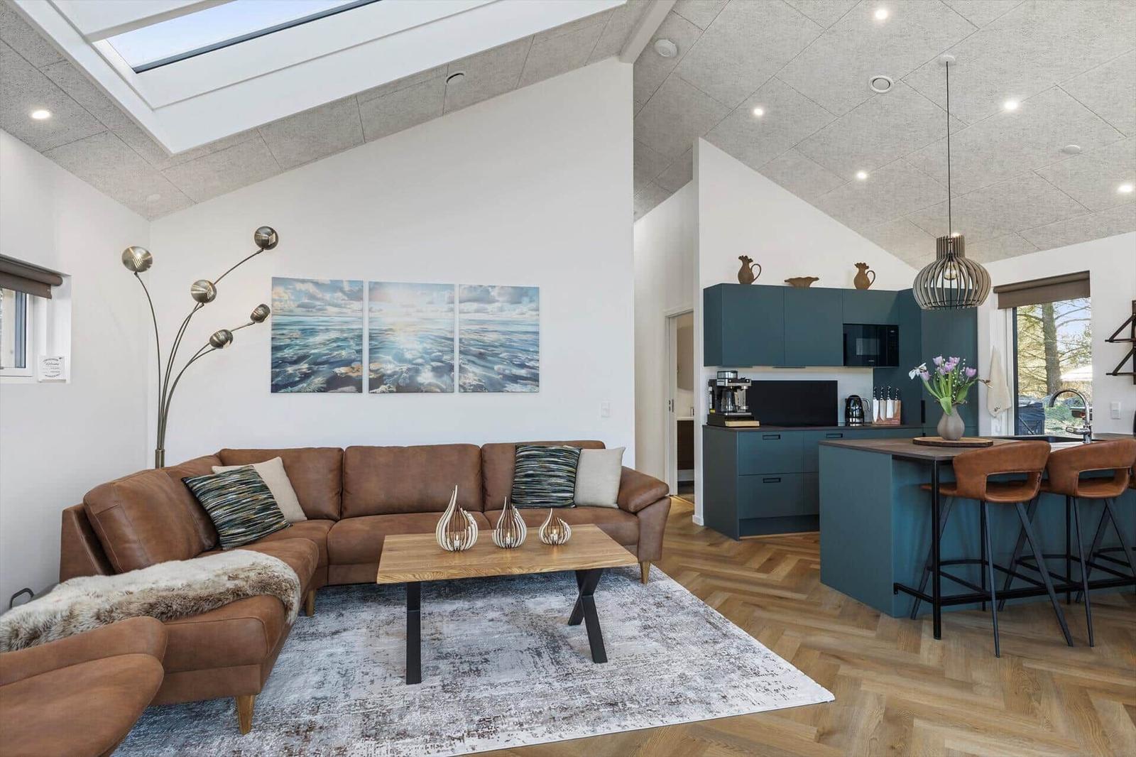 Wohn- und Küchenbereich mit braunem Sofa, Holzboden und blauen Schränken.