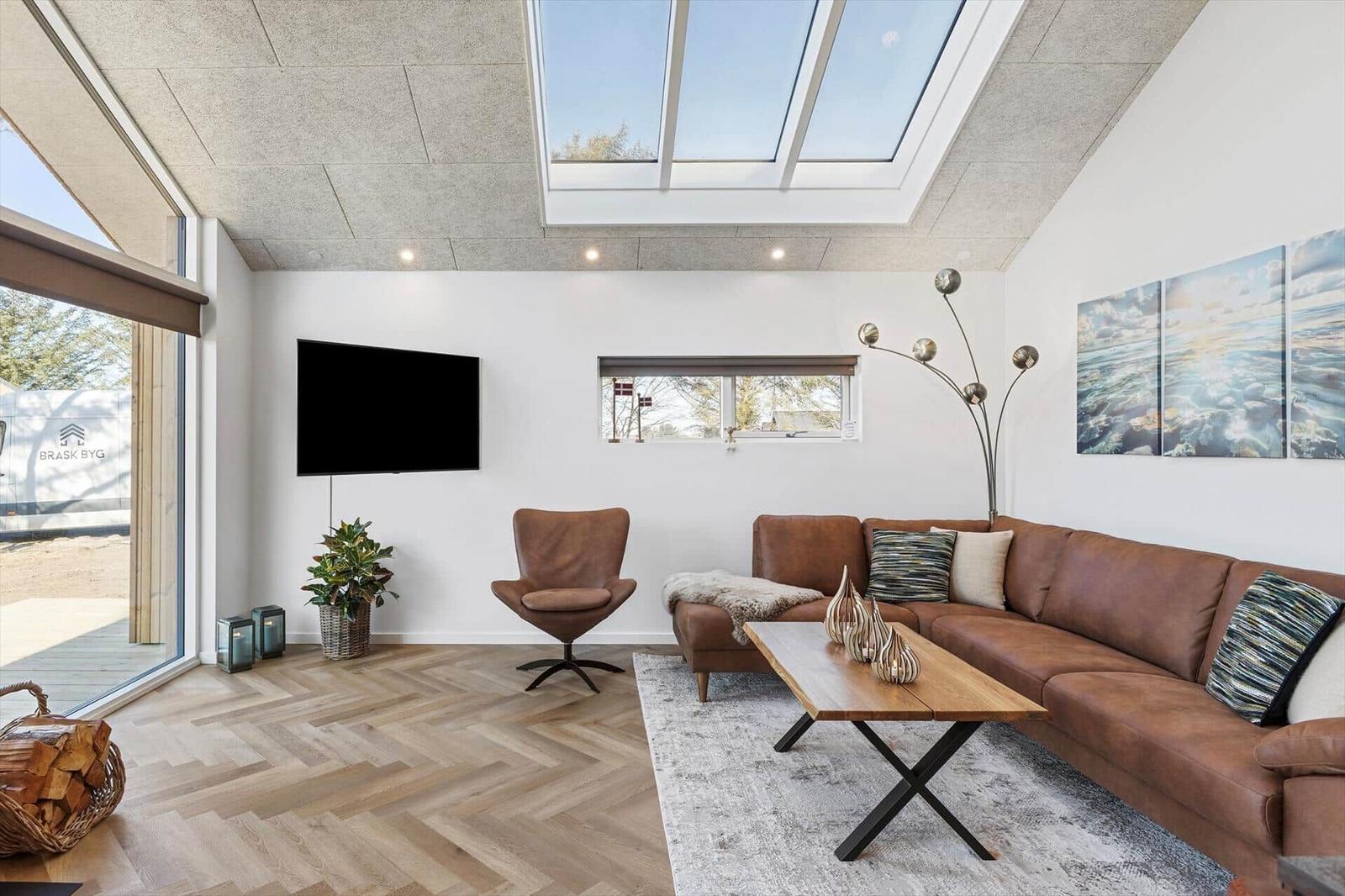 Wohnzimmer mit braunem Sofa, Holzfußboden und Dachfenster.