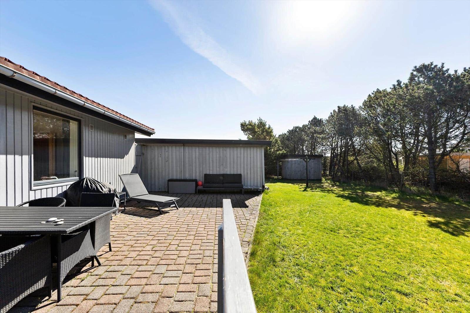 Terrasse mit Garten, Liege und Sitzbank. Hinterhof mit Grünfläche und Bäumen.