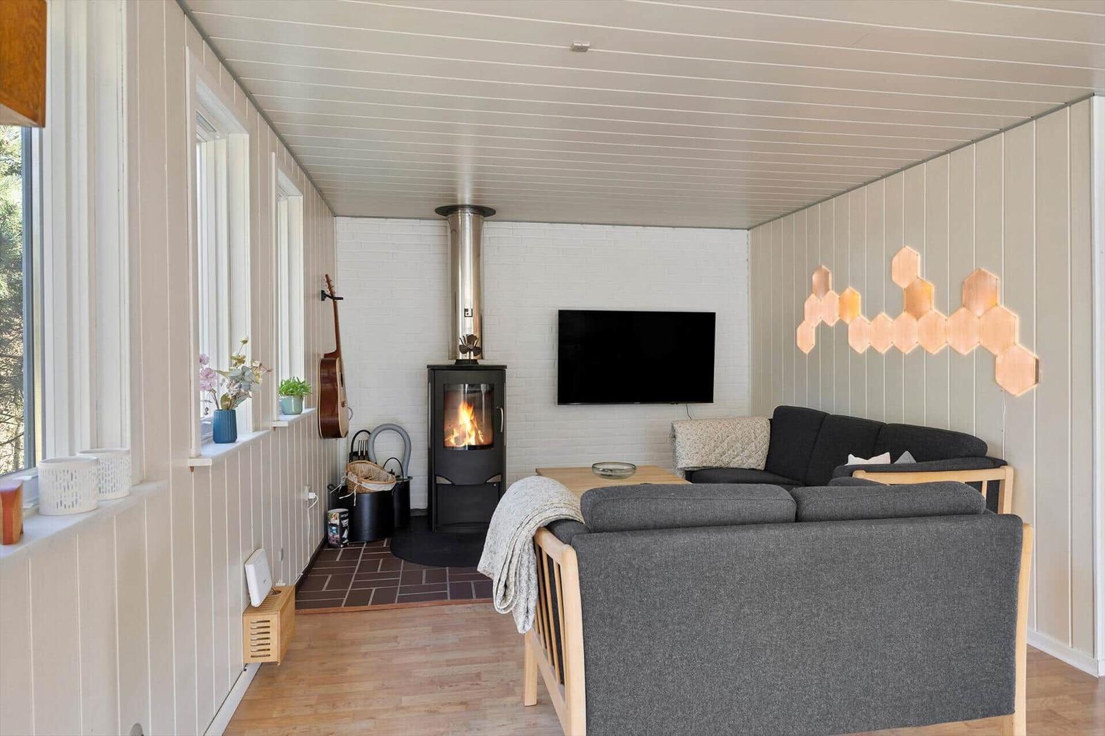 Wohnzimmer mit Kamin, Sofa und Fernseher an weißer Wand.