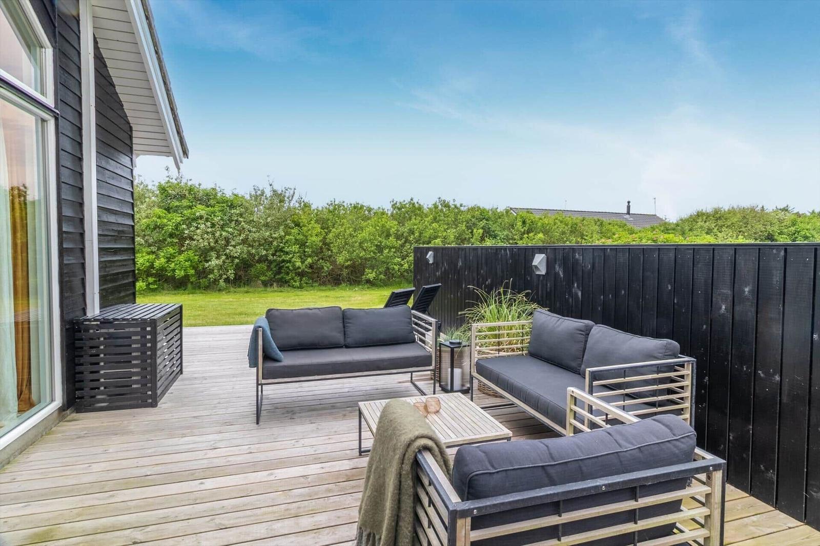 Terrasse mit Sitzgruppe, Holzdecke und Blick auf Grünfläche.