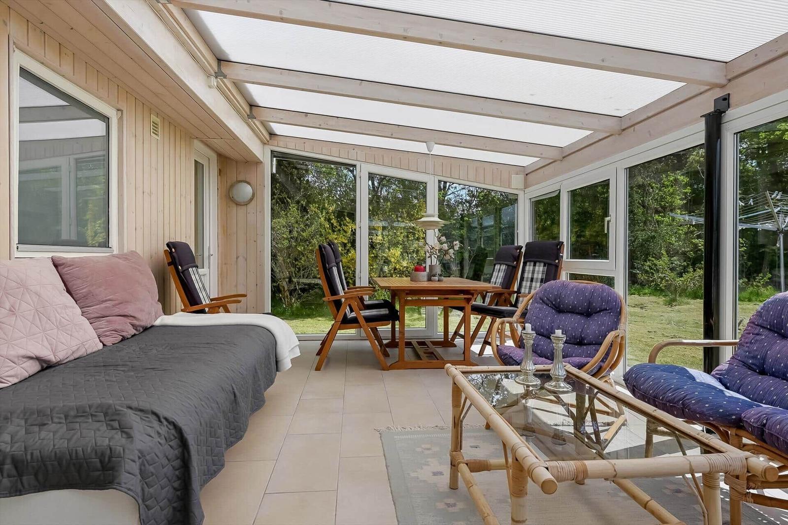 Terrasse mit Sofa, Sitzgruppe und Tisch unter Dach