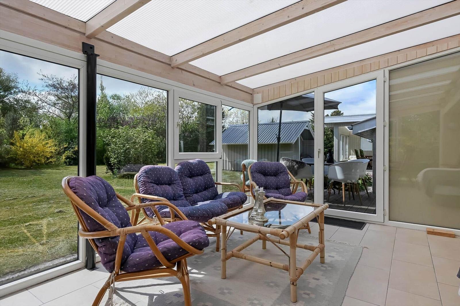Terrasse mit Sitzgruppe und Glasdach. Blick auf Garten und angrenzende Häuser.