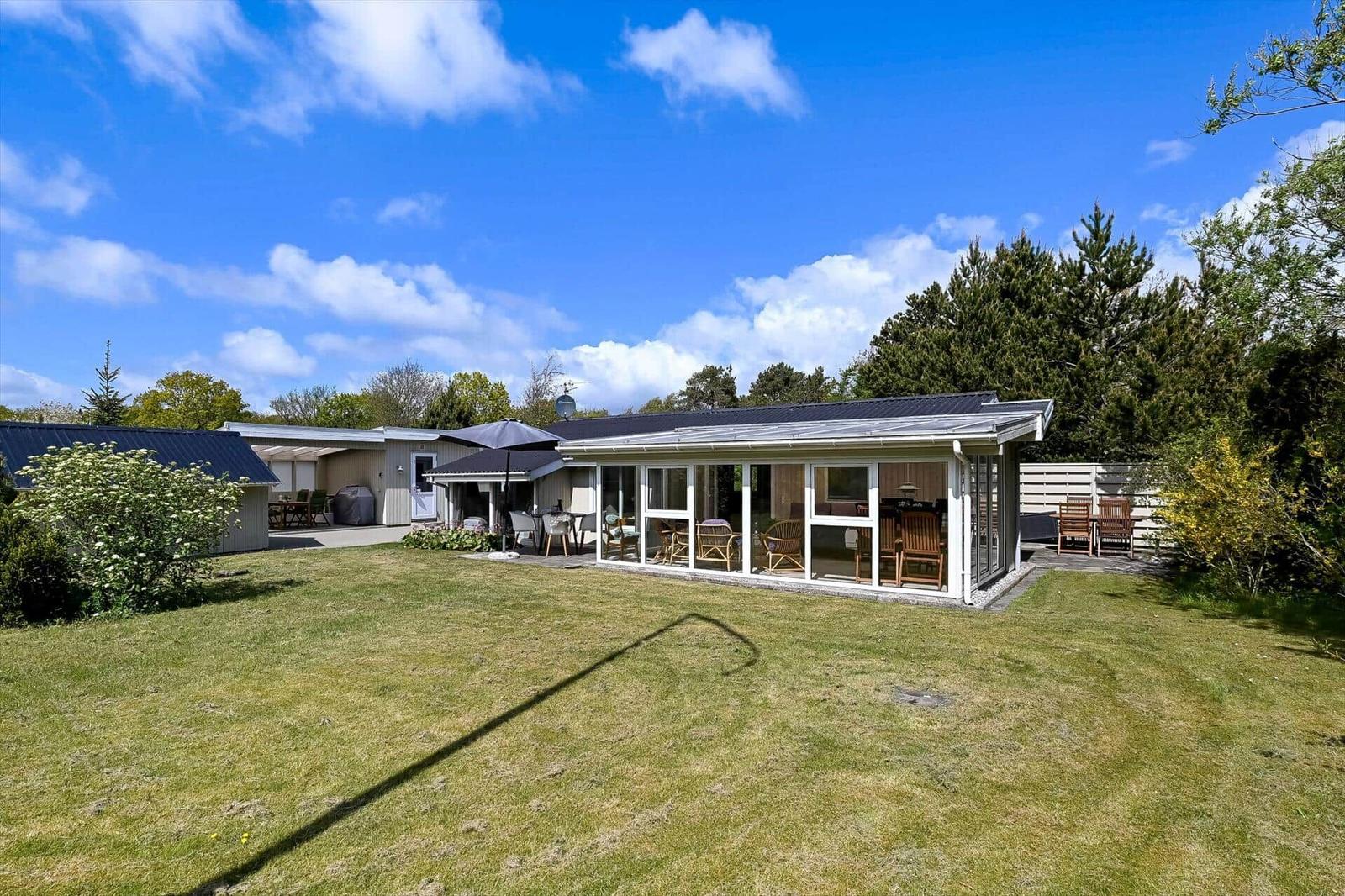 Moderne Ferienhaus mit großem Garten und überdachtem Bereich.