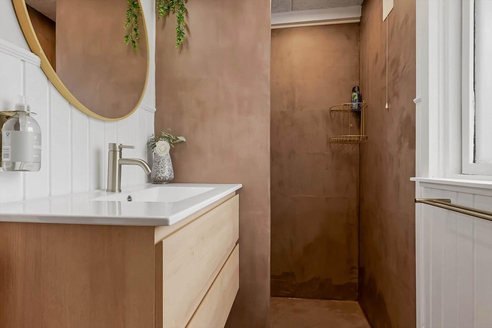 Badezimmer mit Waschbecken, Spiegel und Dusche. Wandfarbe in Terrakotta-Tönen.