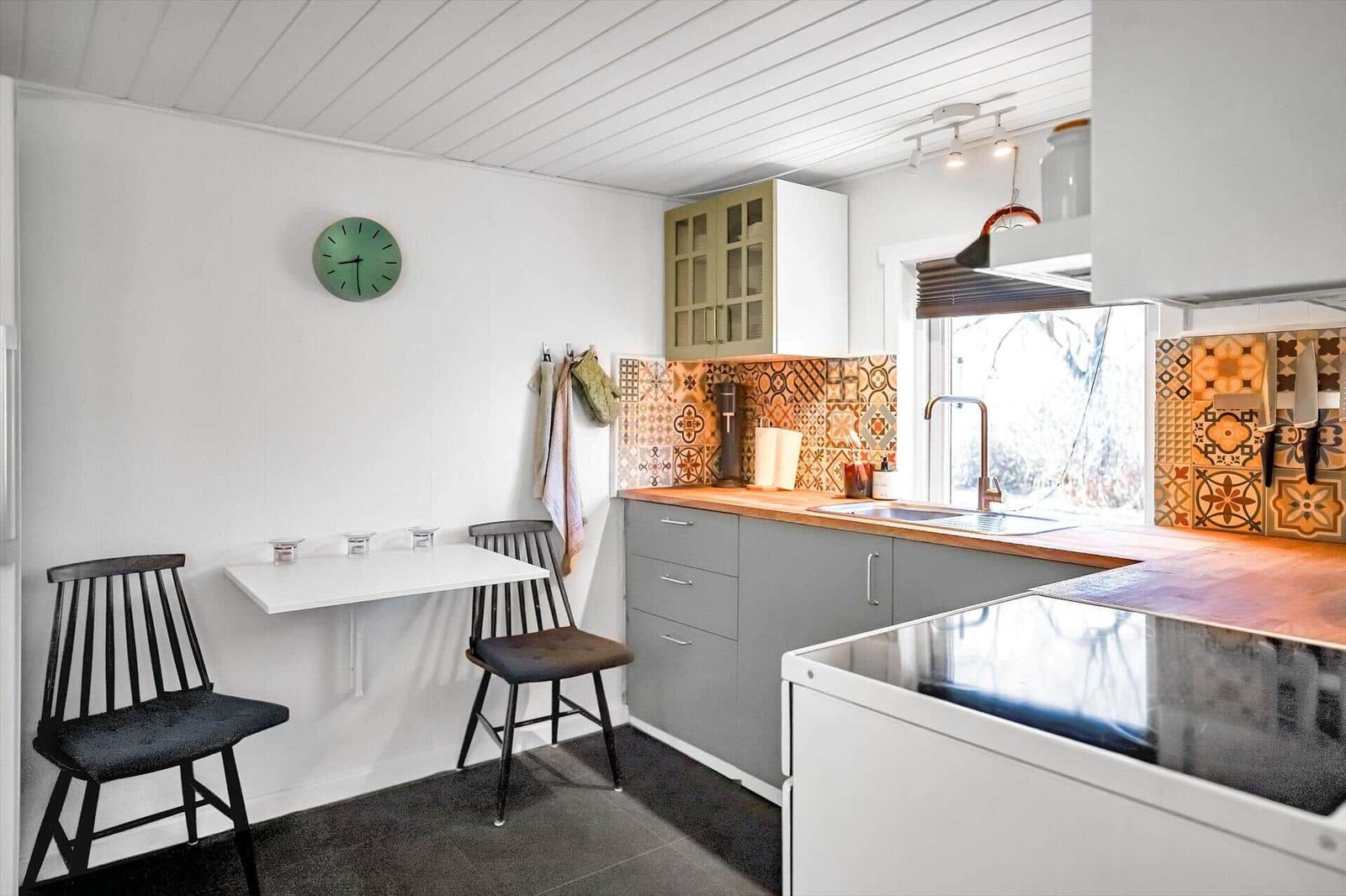 Kitchen with dining area, colorful tiles, and modern equipment.