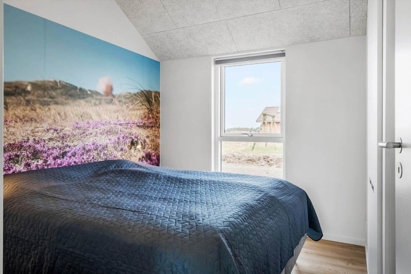 Bedroom with bed, wall mural, and window view of outdoor area.