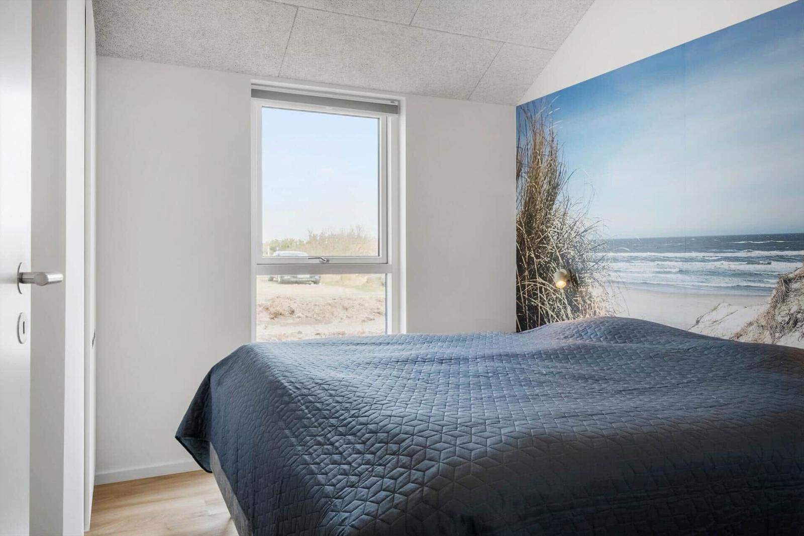 Bedroom with bed, window, and wall mural of beach