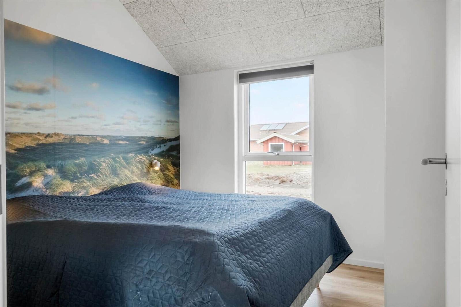 Bedroom with bed, wall mural, and view of red house