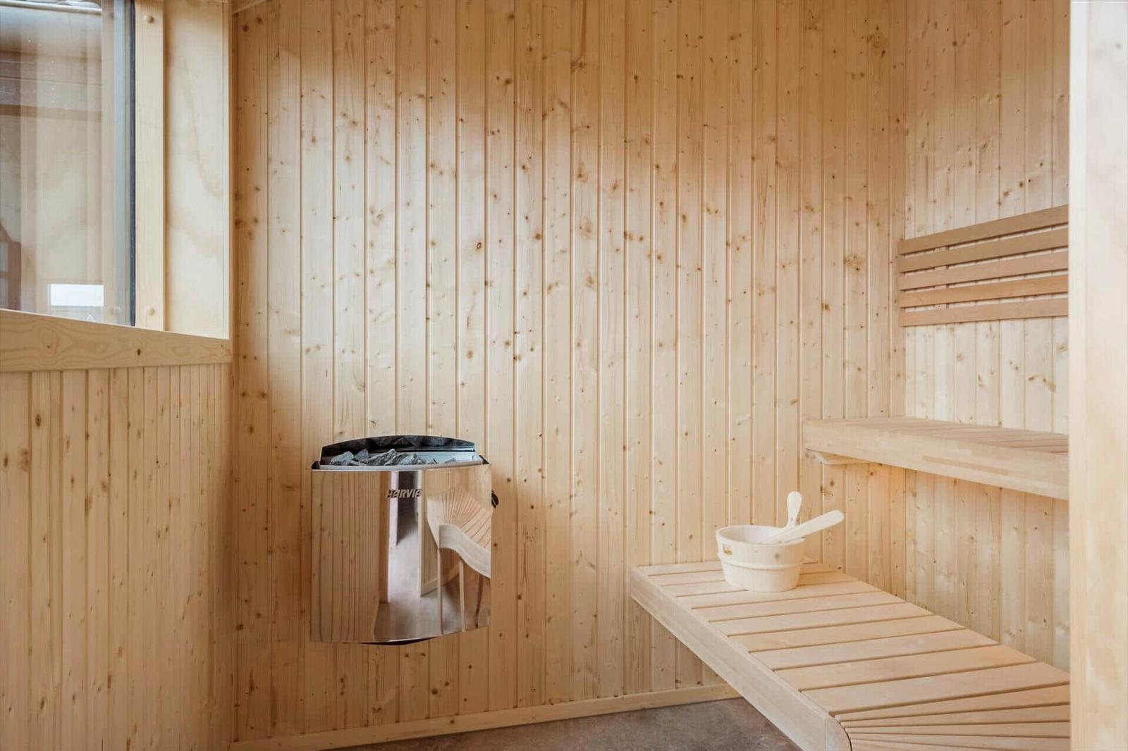 Sauna with wooden walls, bench, and heater