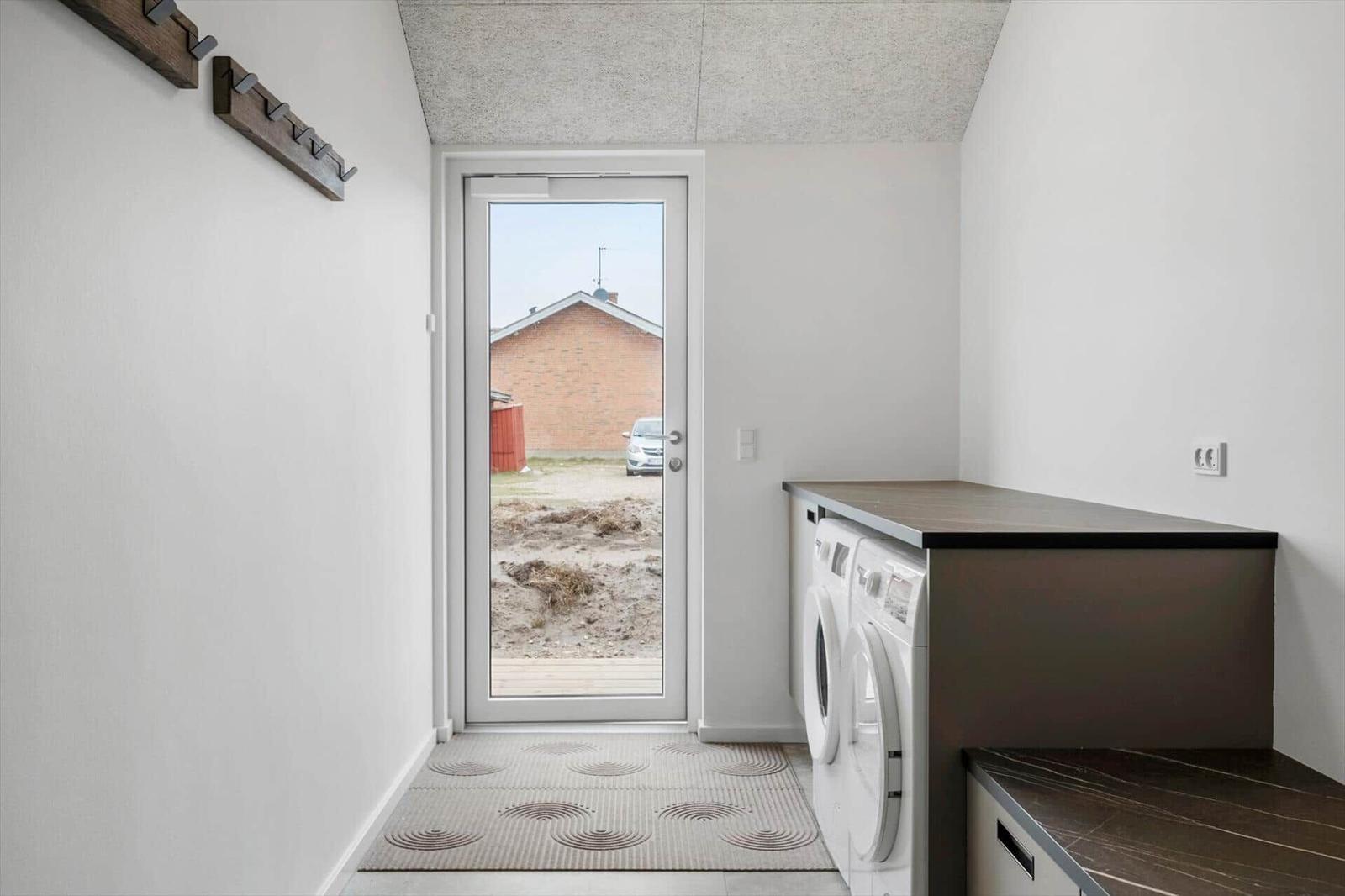 Entrance area with washing machine, door to outdoor area, and coat hooks on the wall.
