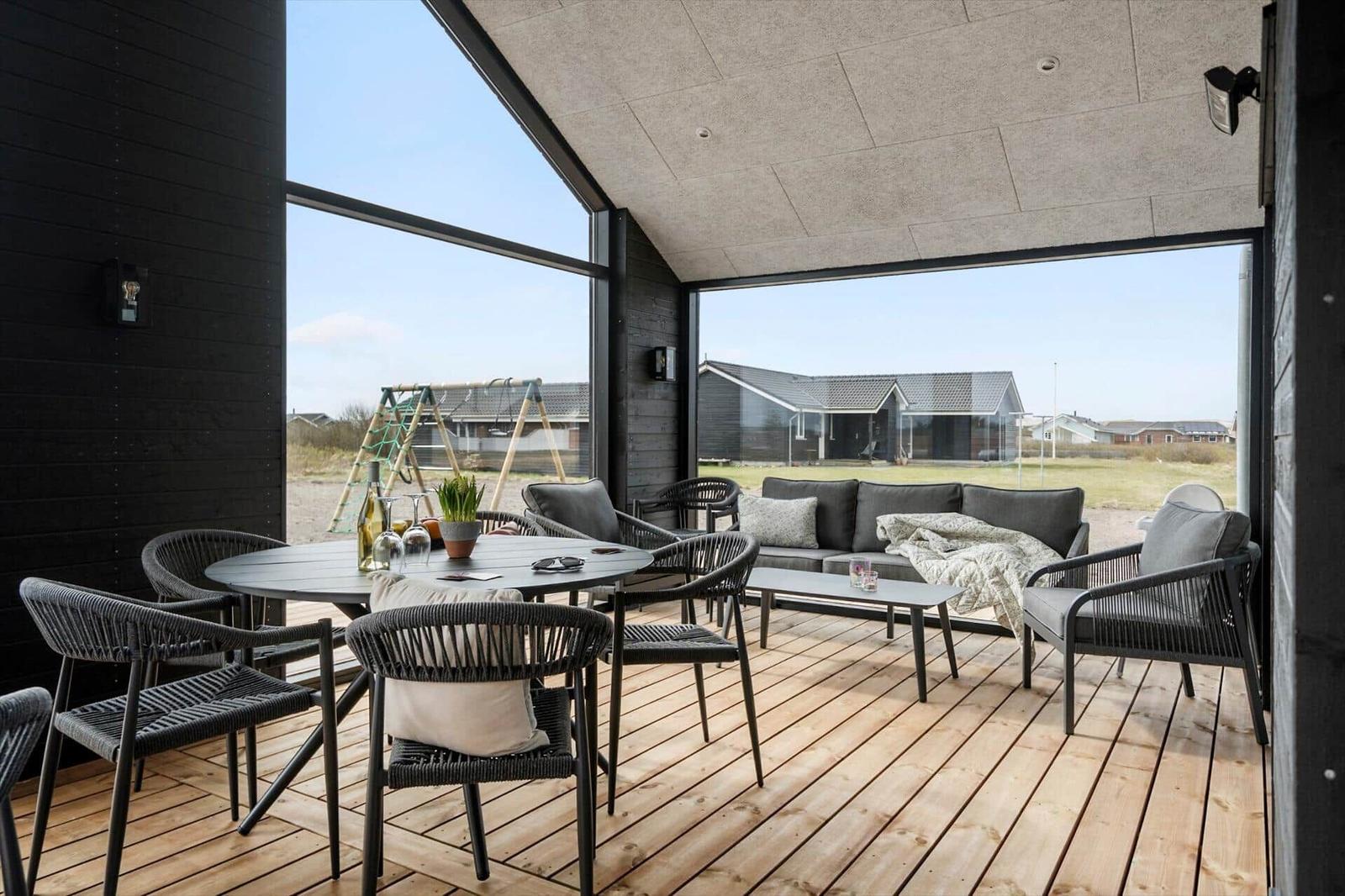 Terrace with seating group, table and chairs. Large glass front with view of outdoor area.