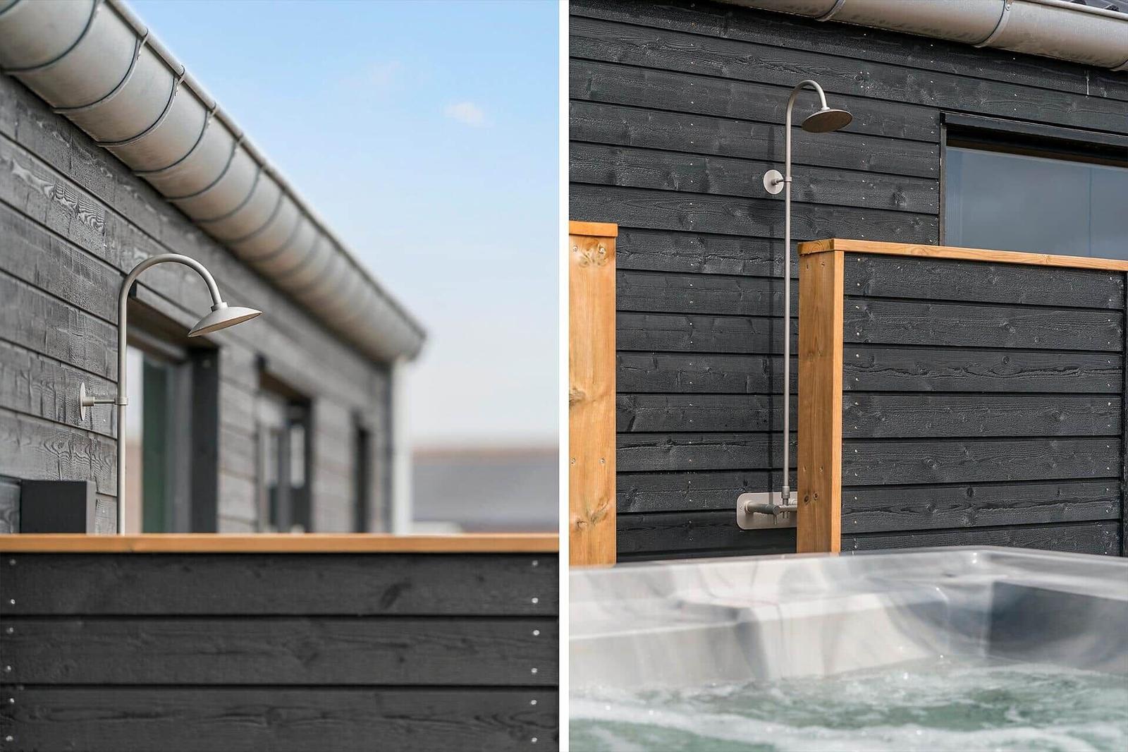 Outdoor shower next to hot tub with wooden frame and dark wood siding.
