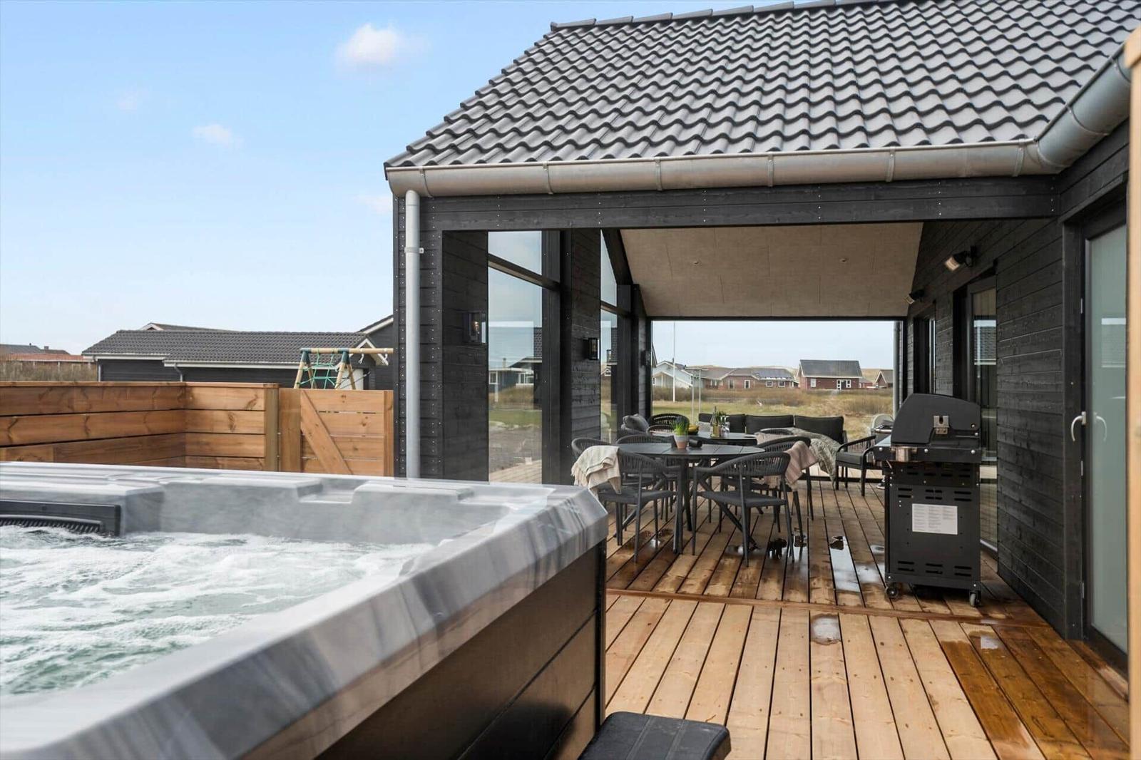 Deck with hot tub, grill, and seating under cover.