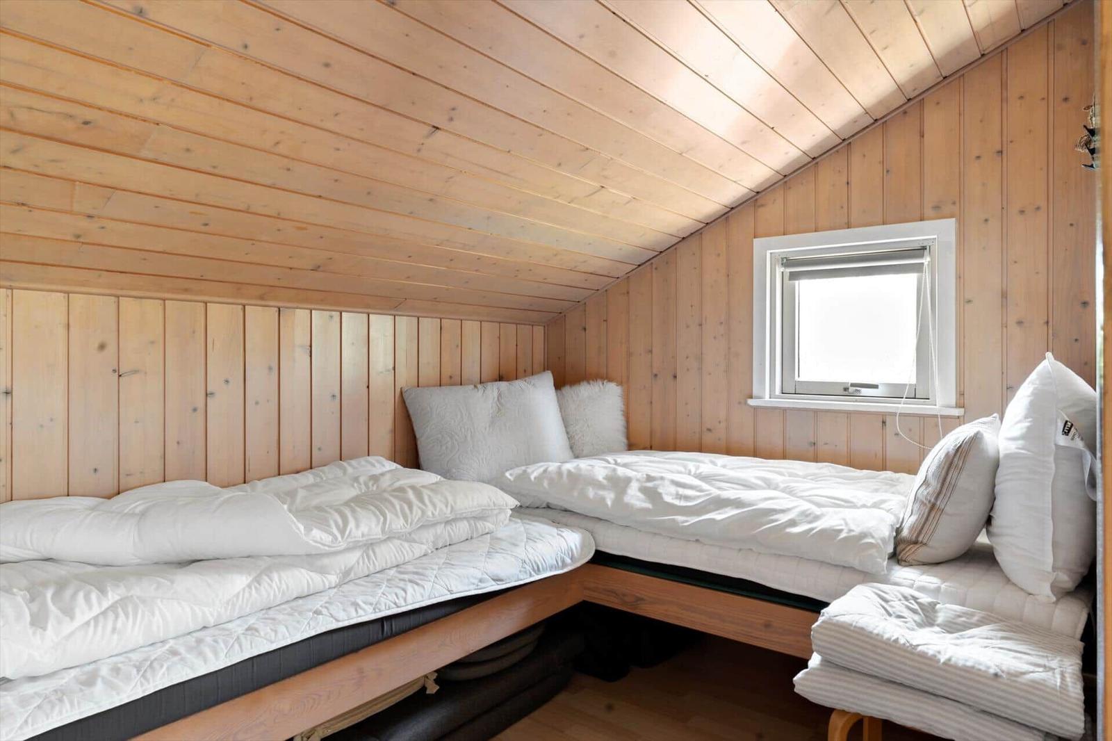 Zimmer mit zwei Matratzen und Holzwänden. Fenster mit Rollladen.