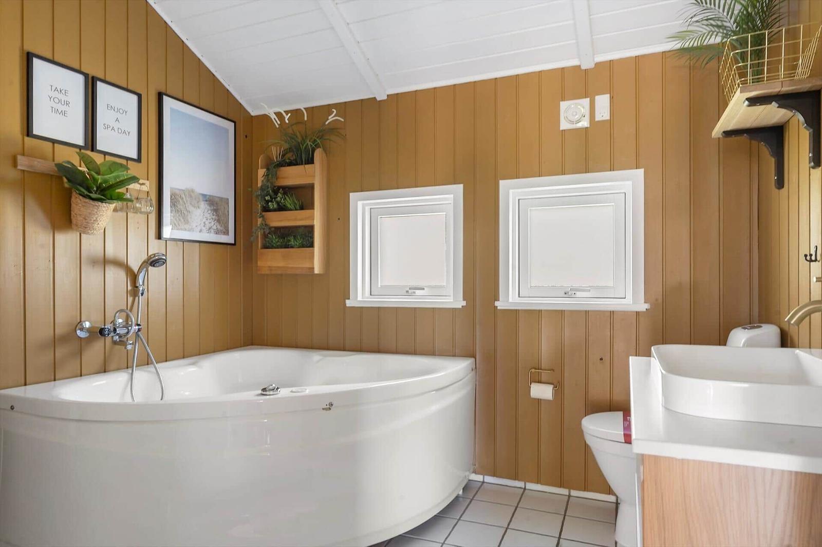 Badezimmer mit Badewanne, Waschbecken und Toilette an Holzwand.