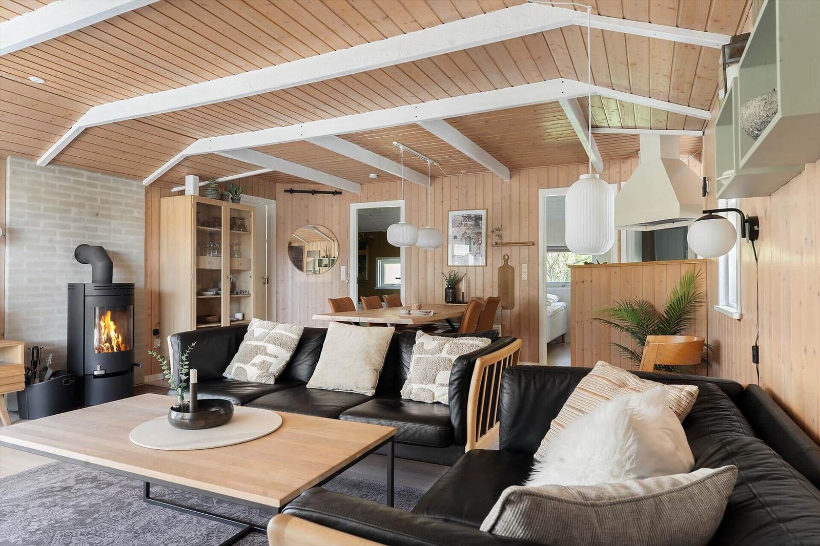 Wohnbereich mit Sofa, Kamin und Holzdecke.