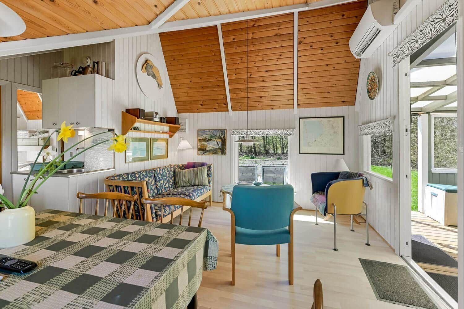 Küche, Essbereich und Wohnzimmer mit Holzdecke und Fenstern.