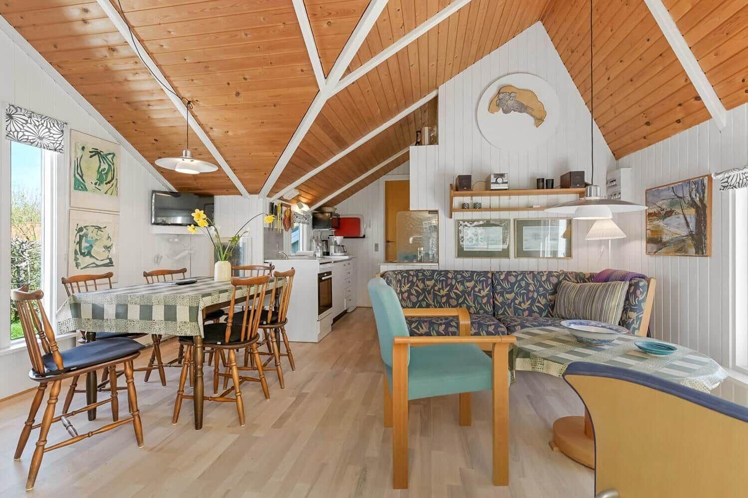 Wohnbereich mit Essbereich, Sofa und Küchenzeile unter Holzdecke.