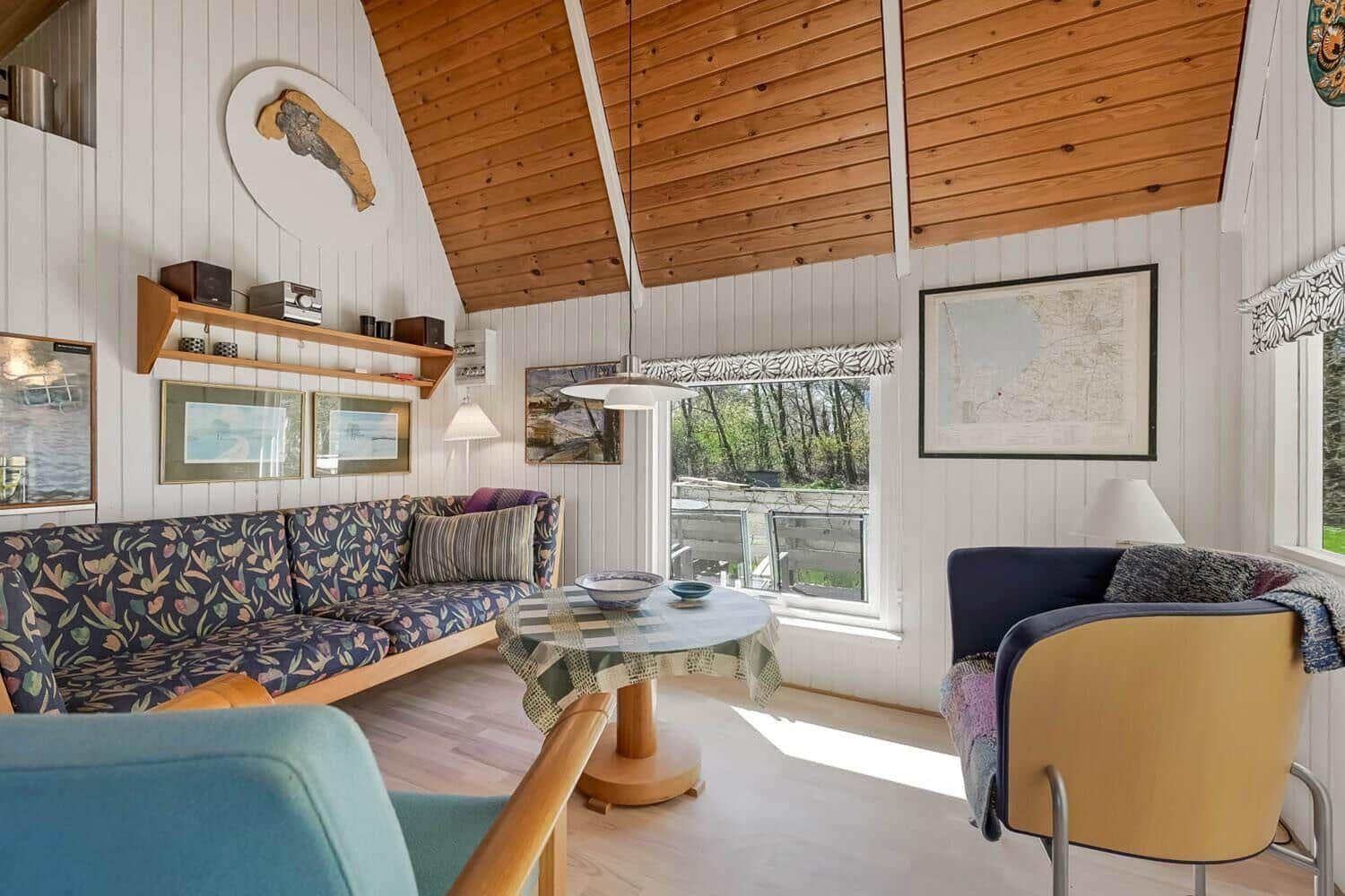 Wohnzimmer mit Sofa, Tisch und Sessel unter Holzdecke.