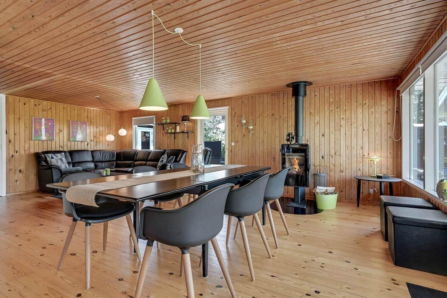 Dining room with table, chairs, and fireplace in wooden house.