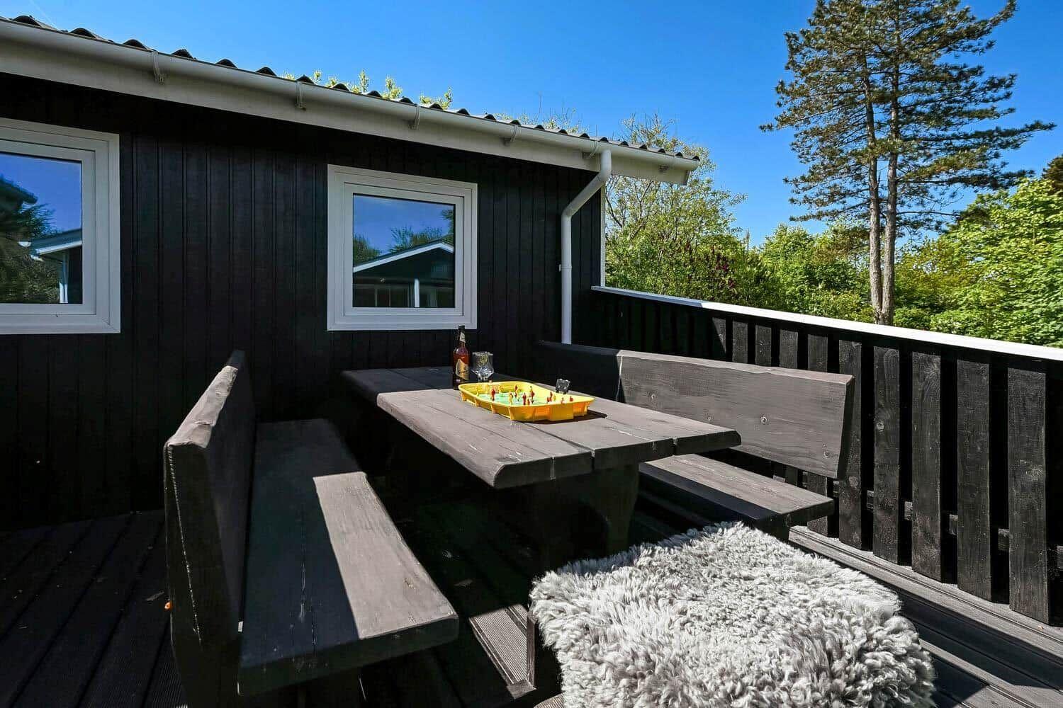 Deck with table, benches, and floor. Yellow board game and bottle on it.