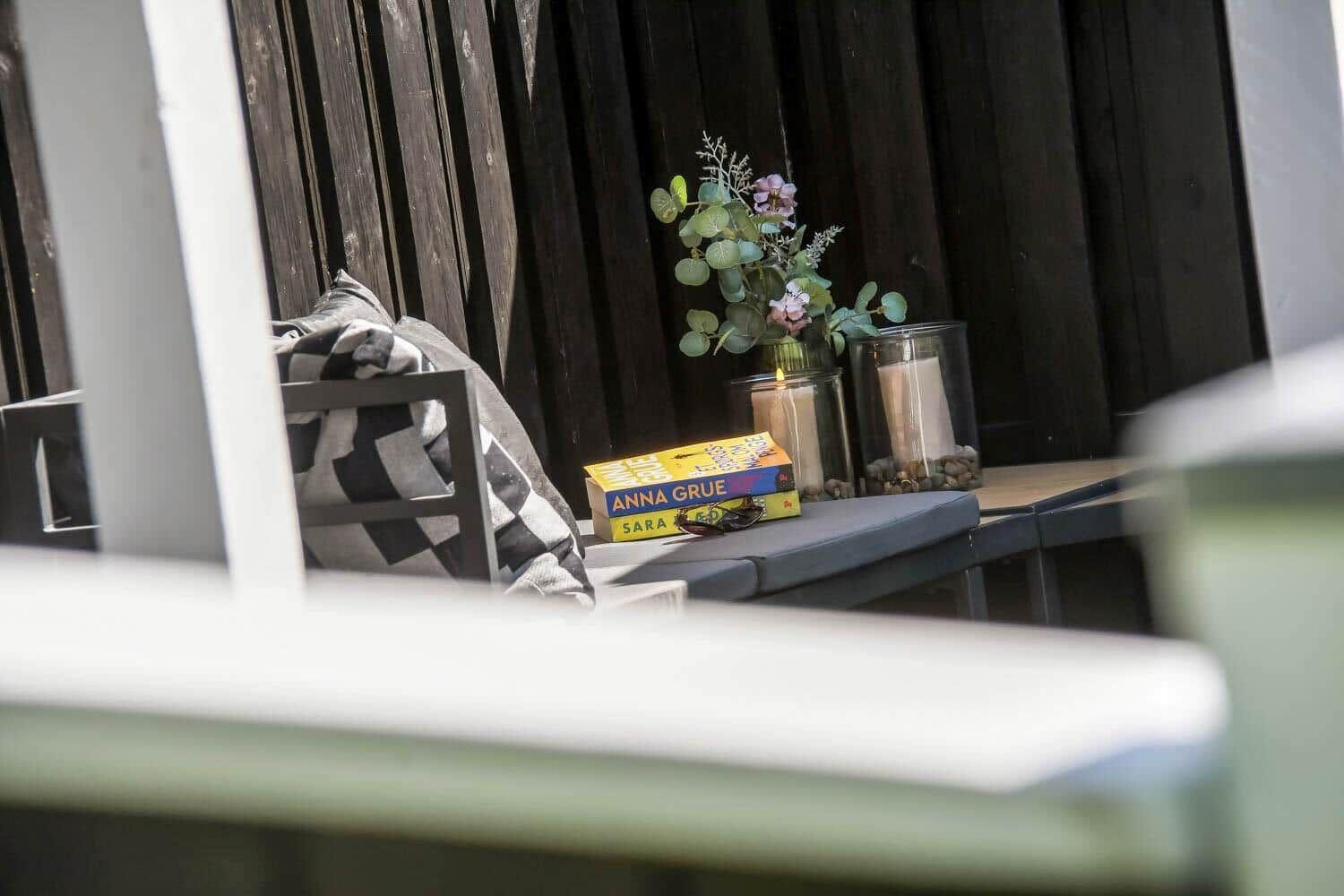 Outdoor seating area with book and floral arrangement against dark wooden fence.