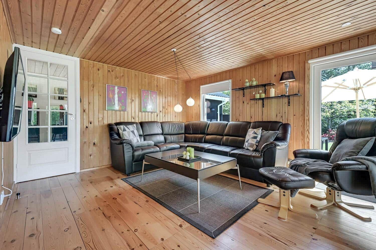 Living room with wood walls, L-shaped sofa, and glass table