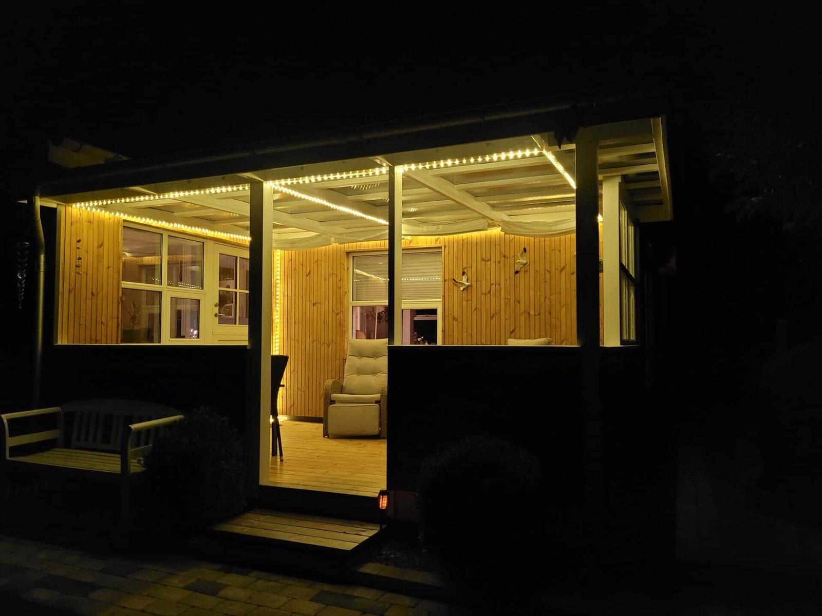 Haus mit beleuchteter Veranda und Sitzgelegenheit im Inneren.