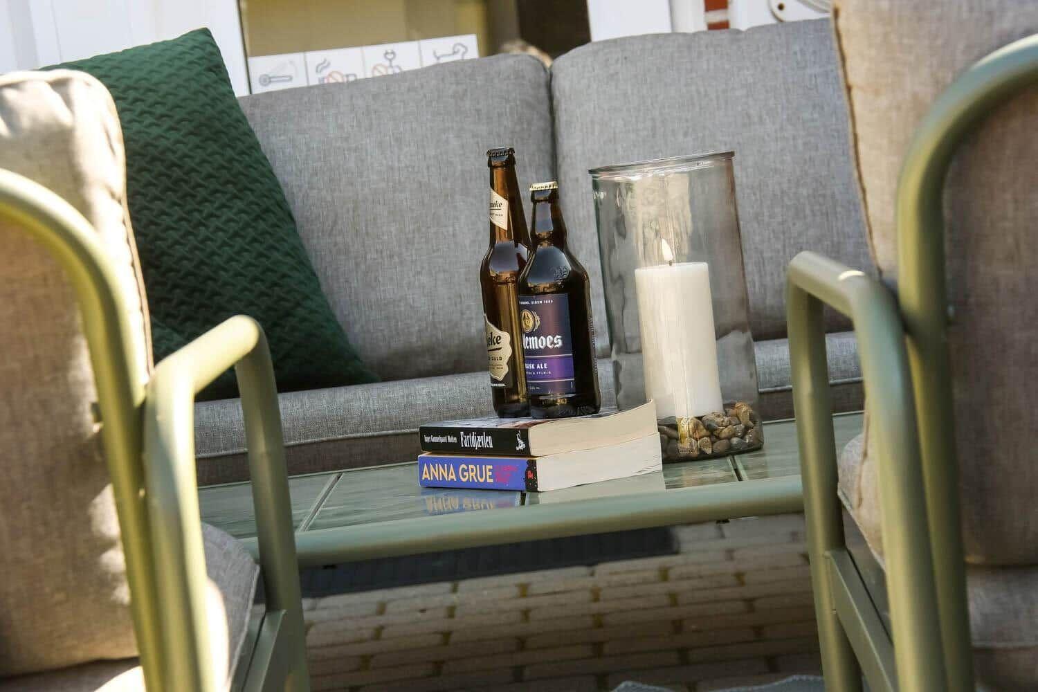 Gelber Sitzbereich mit Tisch, darauf Bücher, Flaschen und eine brennende Kerze.