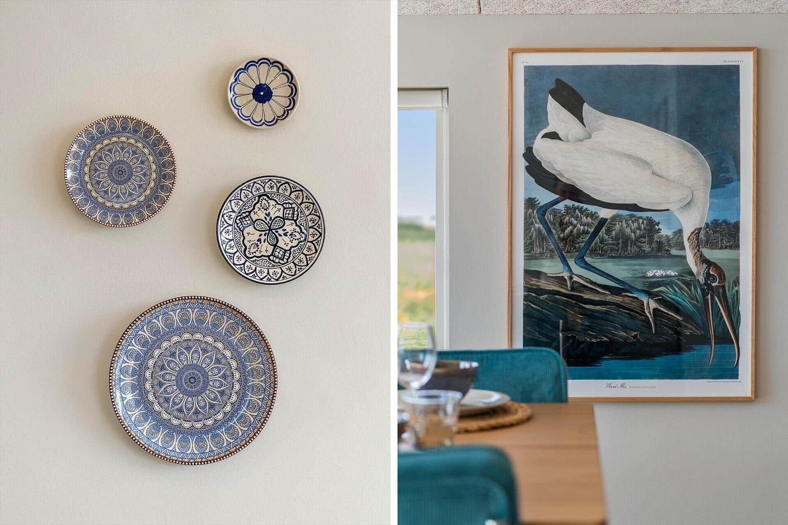 Wand mit vier blau-weißen Keramikplatten und ein Bild eines Vogels an der Wand.