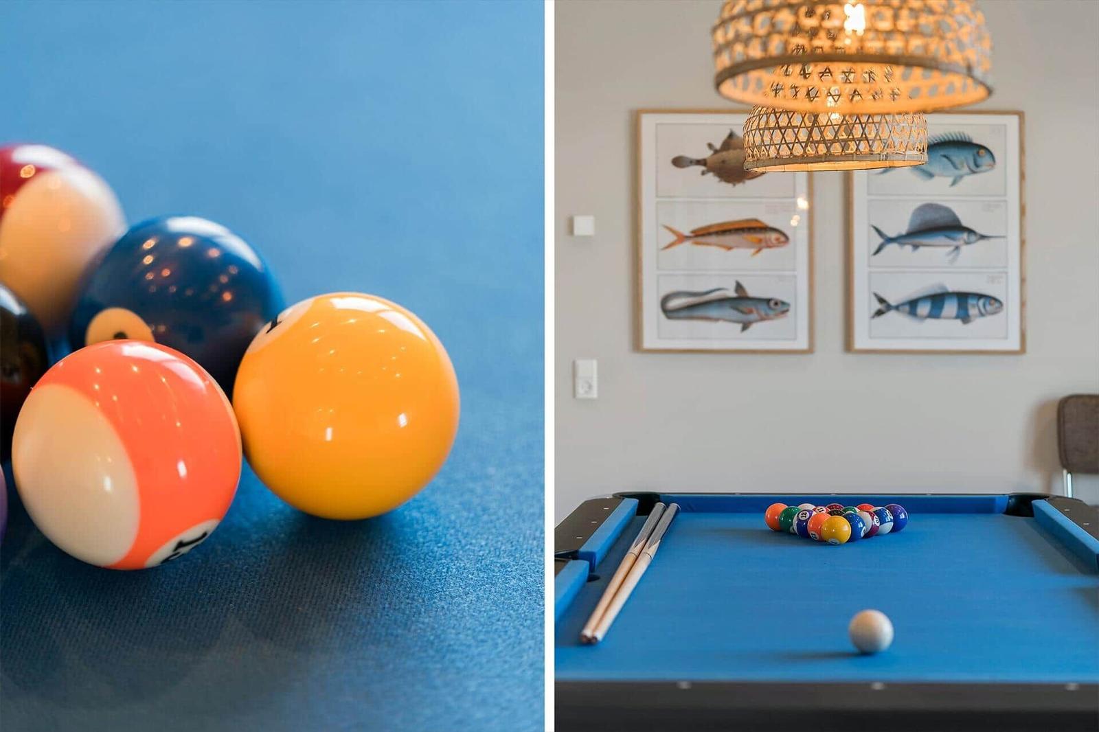 Blauer Billardtisch mit Bällen und Stöcken. Wand mit Fischposter und Deckenleuchte.