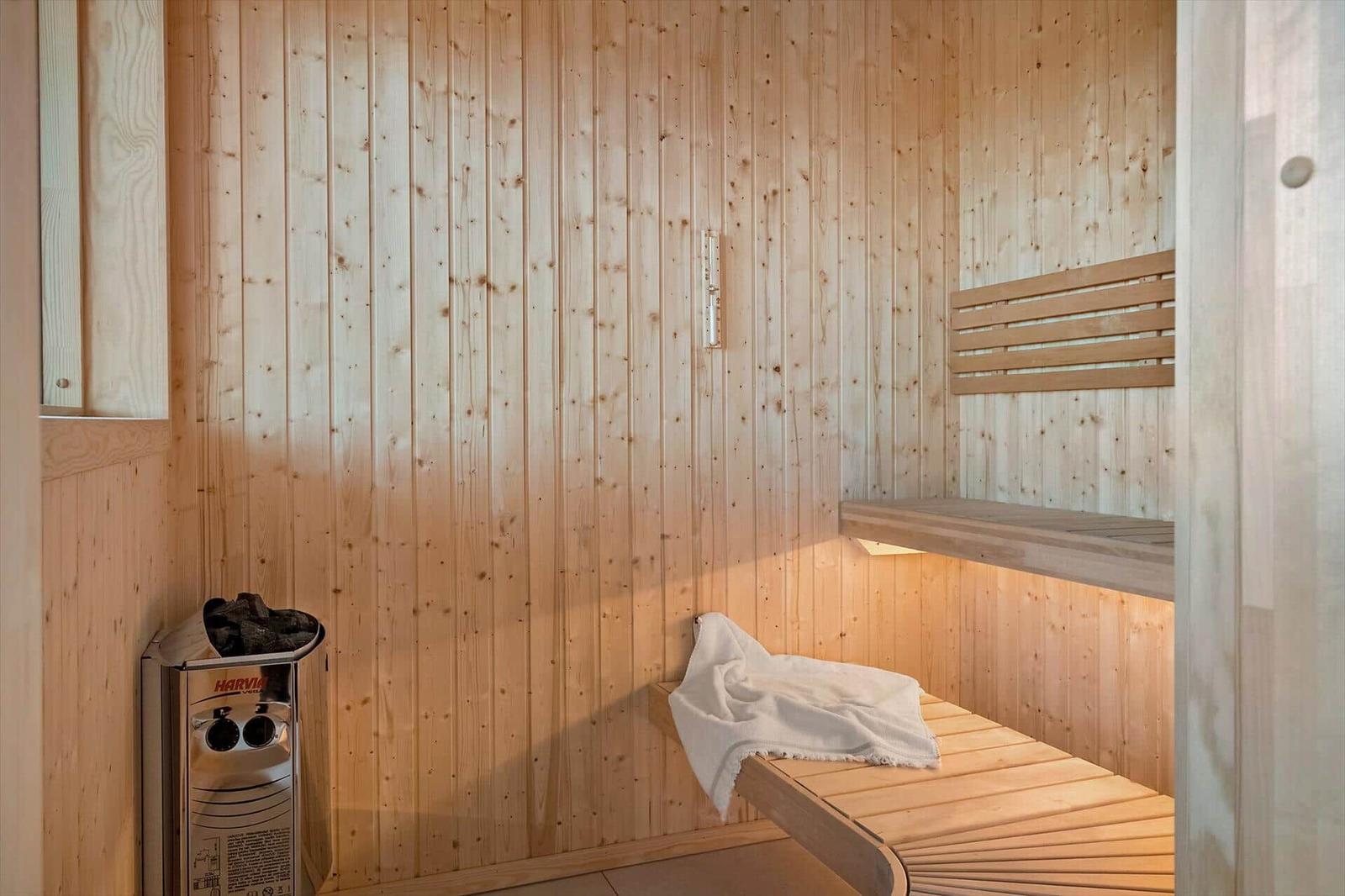 Sauna mit Holzwand, Sitzbank und Heizgerät. Ein Handtuch liegt auf der Bank.