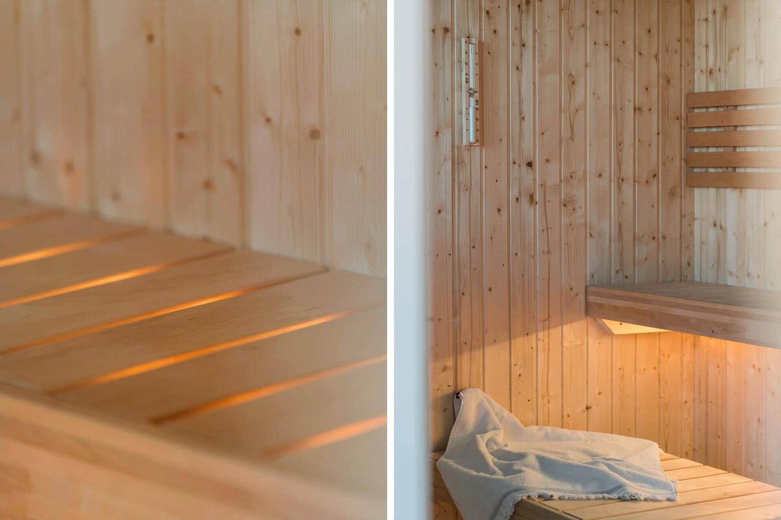 Sauna mit Holzwand und Sitzbänken. Ein Handtuch liegt auf der untersten Bank.