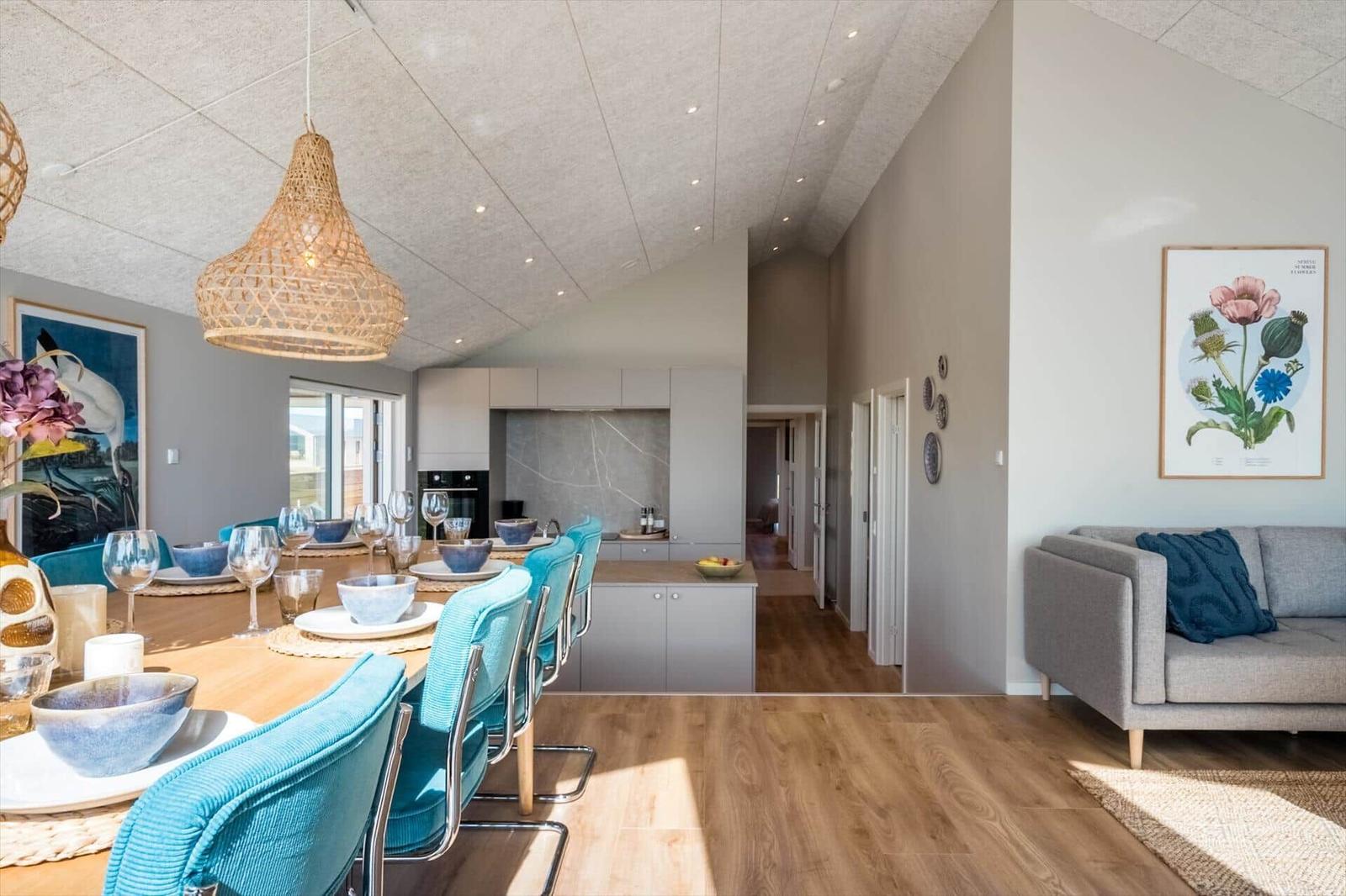 Essbereich mit Tisch, Stühlen und Küchenbereich. Wohnzimmer mit Sofa und Wandbild.