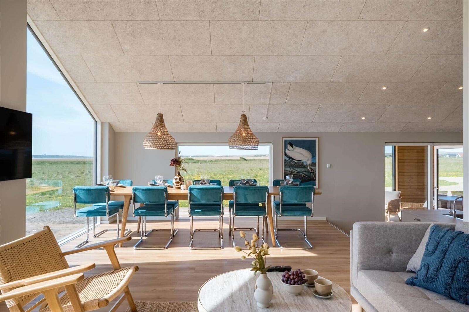 Esszimmer mit blauen Stühlen und großem Fenster. Wohnbereich mit Sofa und runden Tisch.