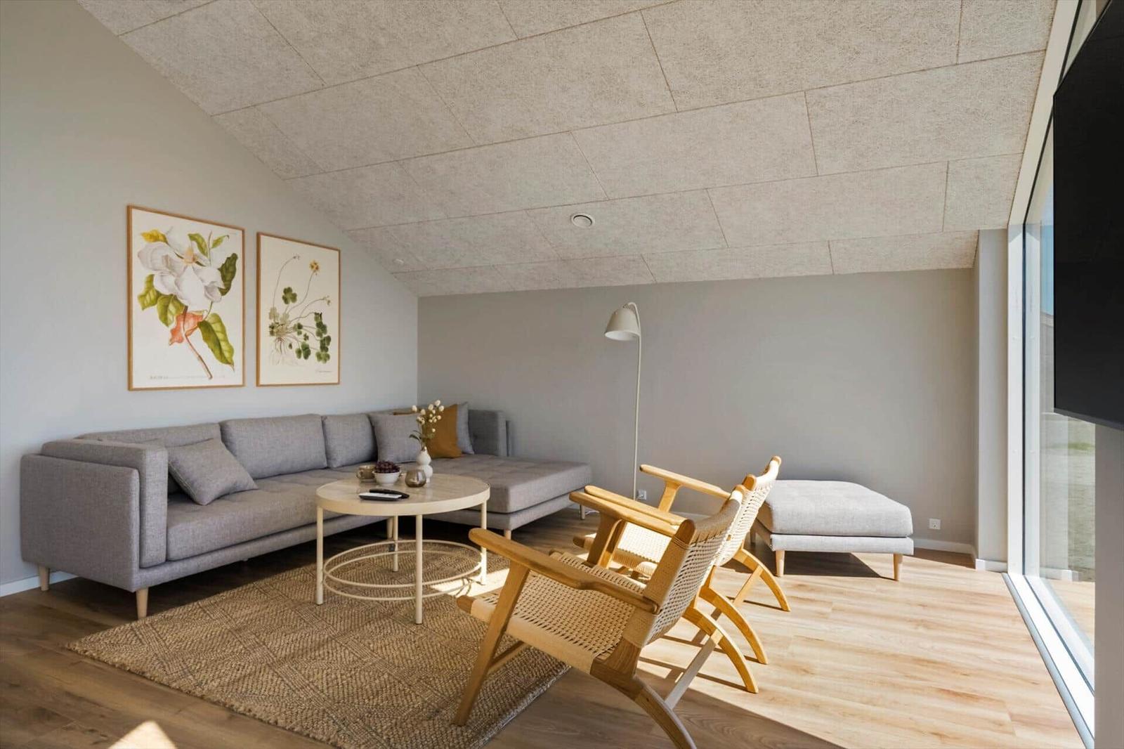 Wohnzimmer mit Sofa, zwei Stühlen, Tisch und Wandbildern.