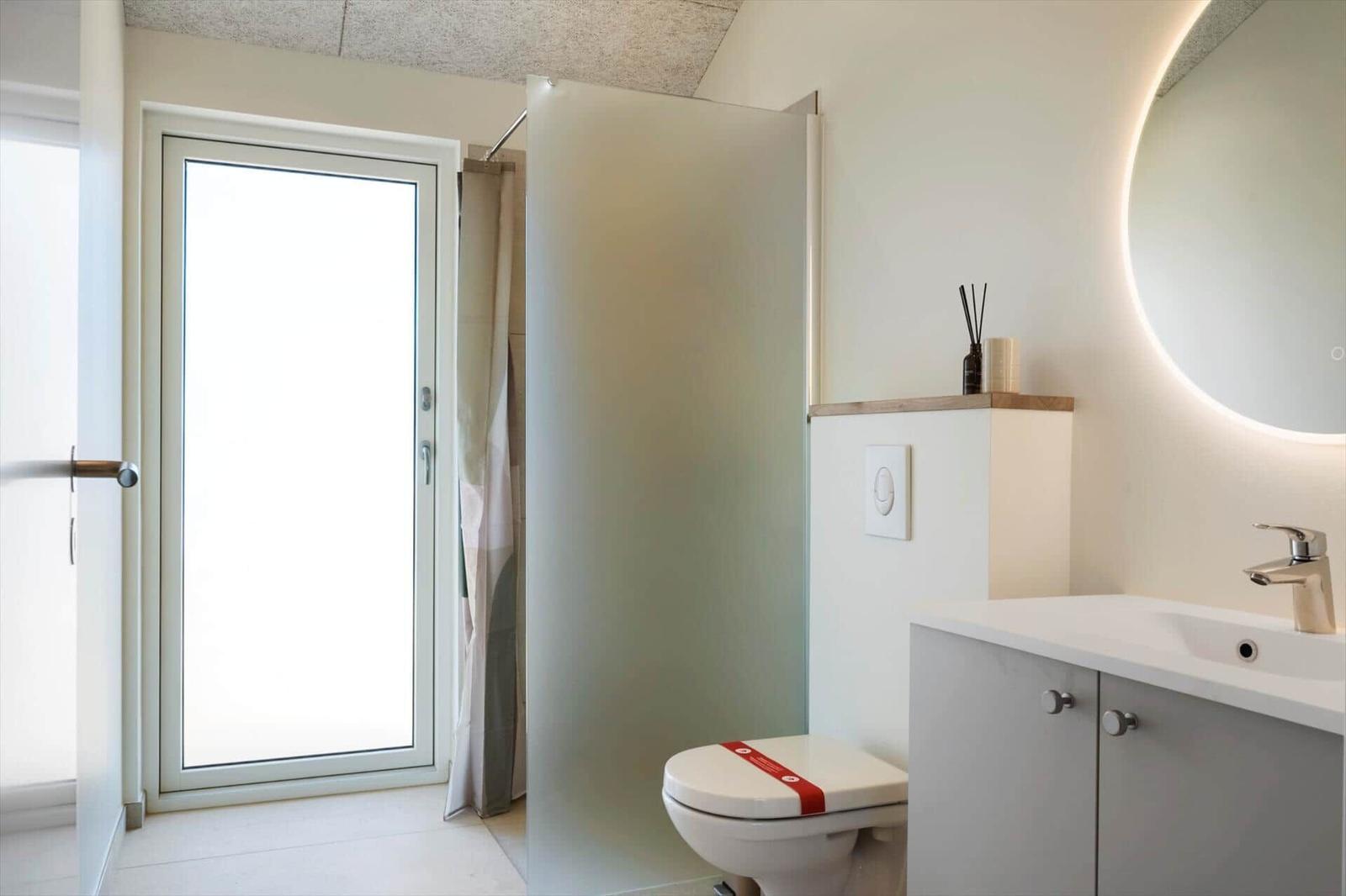 Badezimmer mit Toilette, Waschbecken und Dusche mit Fenster.
