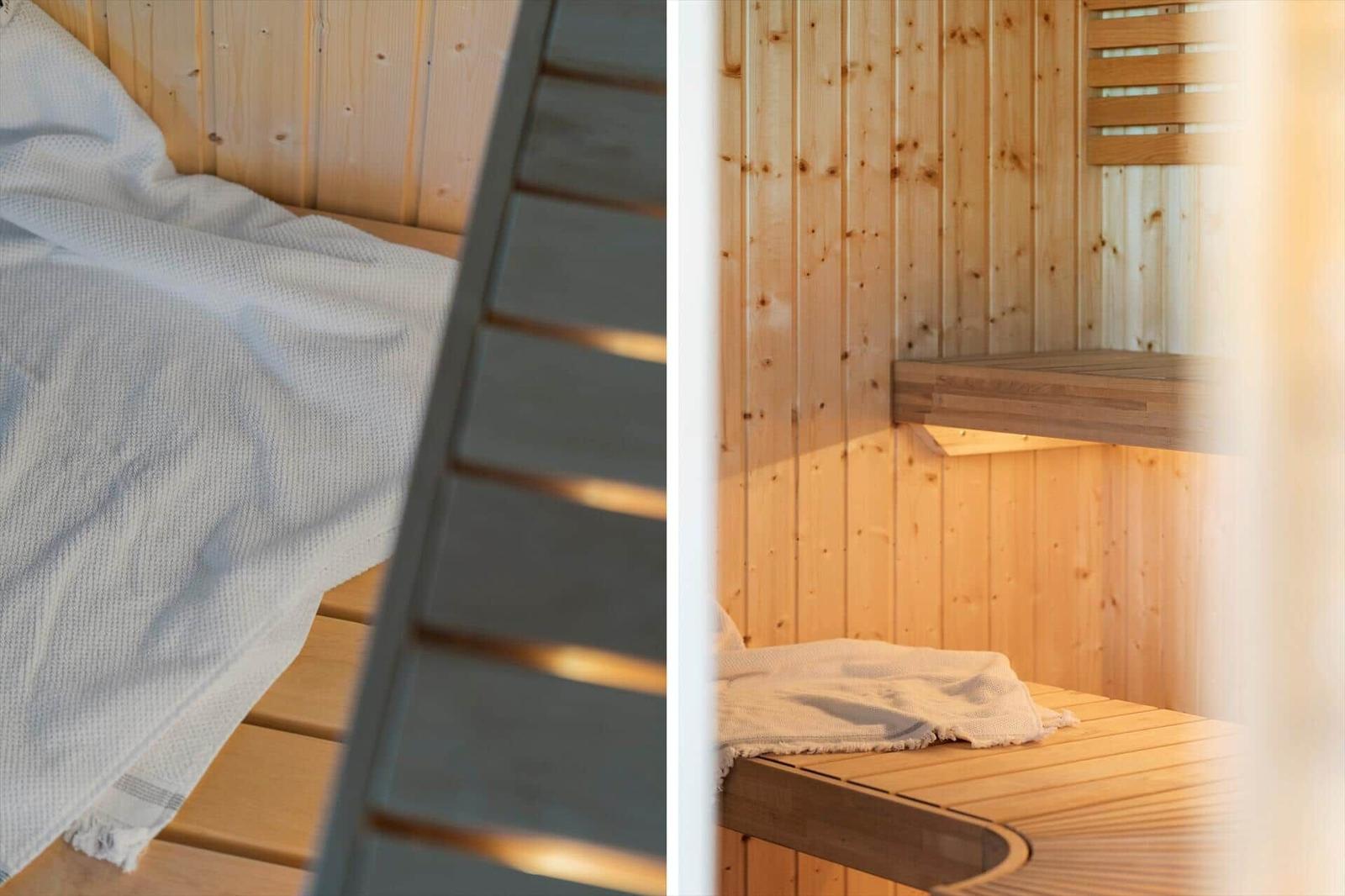 Holzsauna mit Sitzbank und Deckenbalken. Bett mit weißer Decke und Holzrahmen.