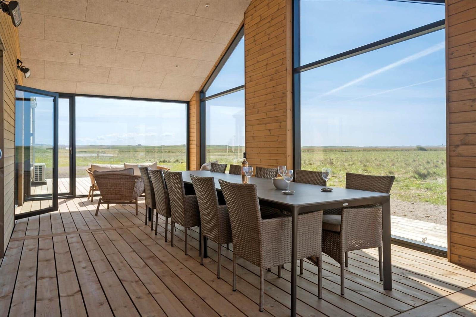 Großer Essbereich mit Tisch und Stühlen. Große Fenster mit Blick auf eine Wiese.