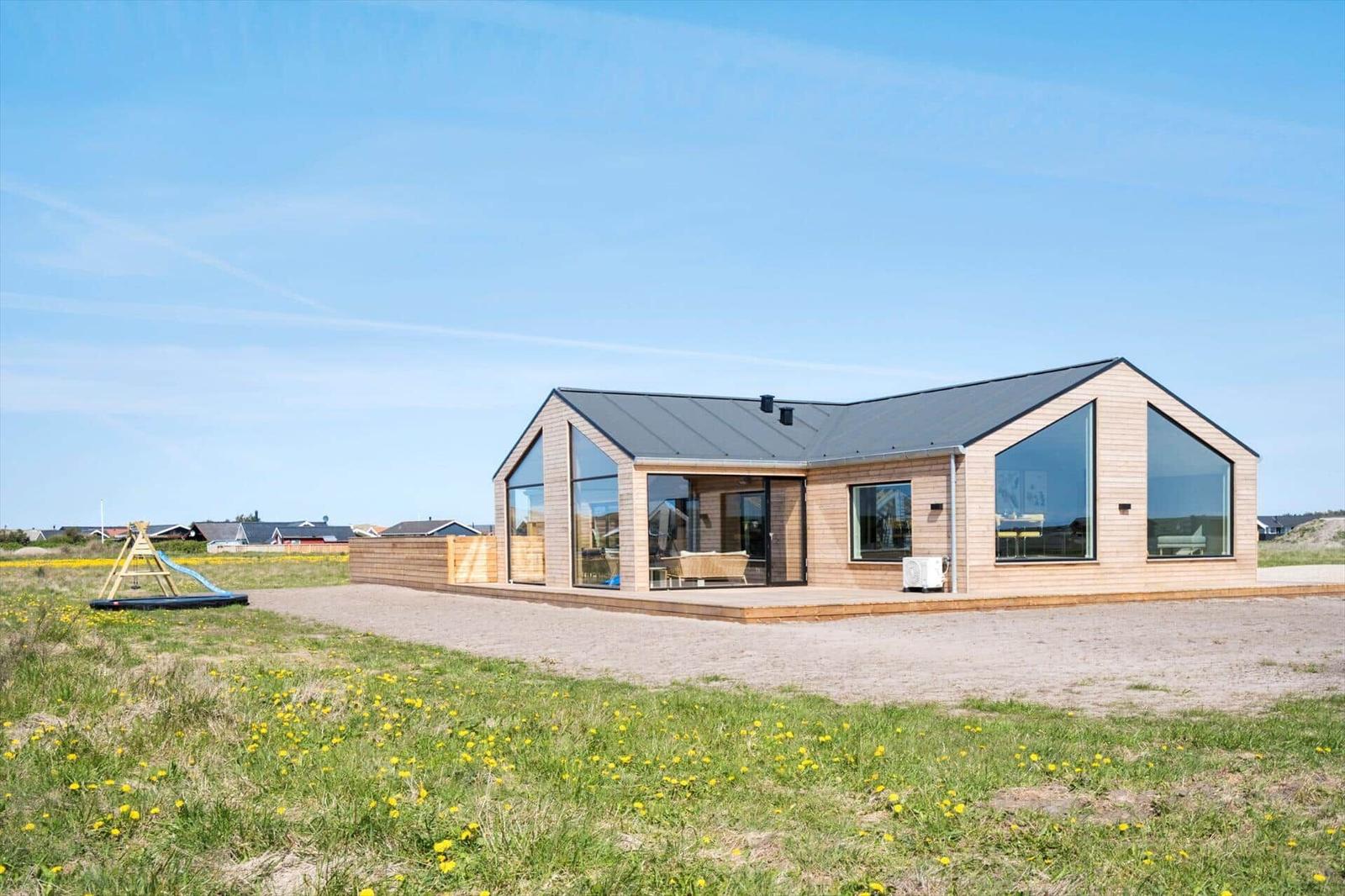 Moderne Holzhütte mit großem Glasbereich und Terrasse im Freien.