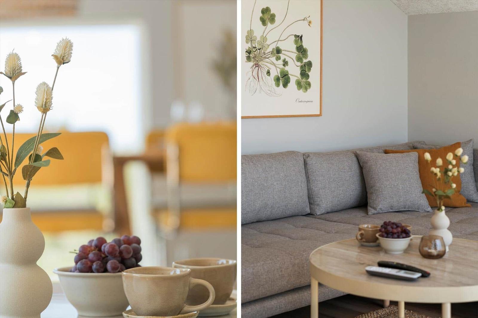 Grauer Sofa mit Kissen, runder Tisch, Obst und Blumen im Wohnbereich.