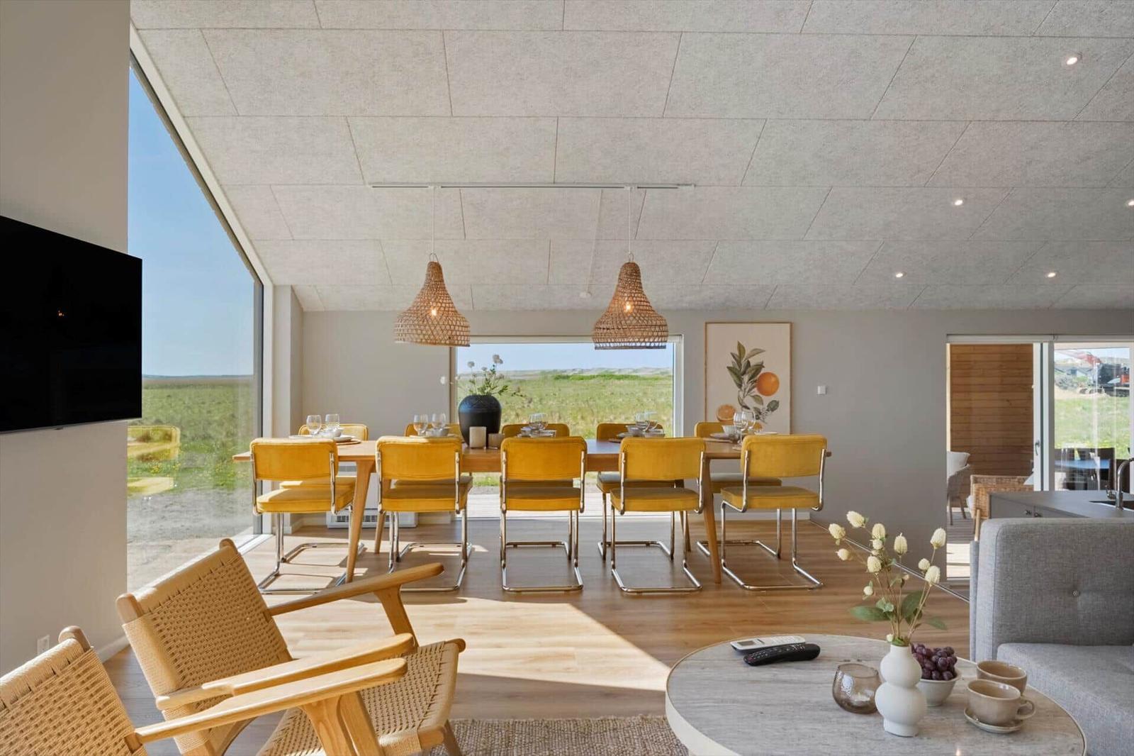 Esszimmer mit gelben Stühlen und Blick auf die Landschaft.