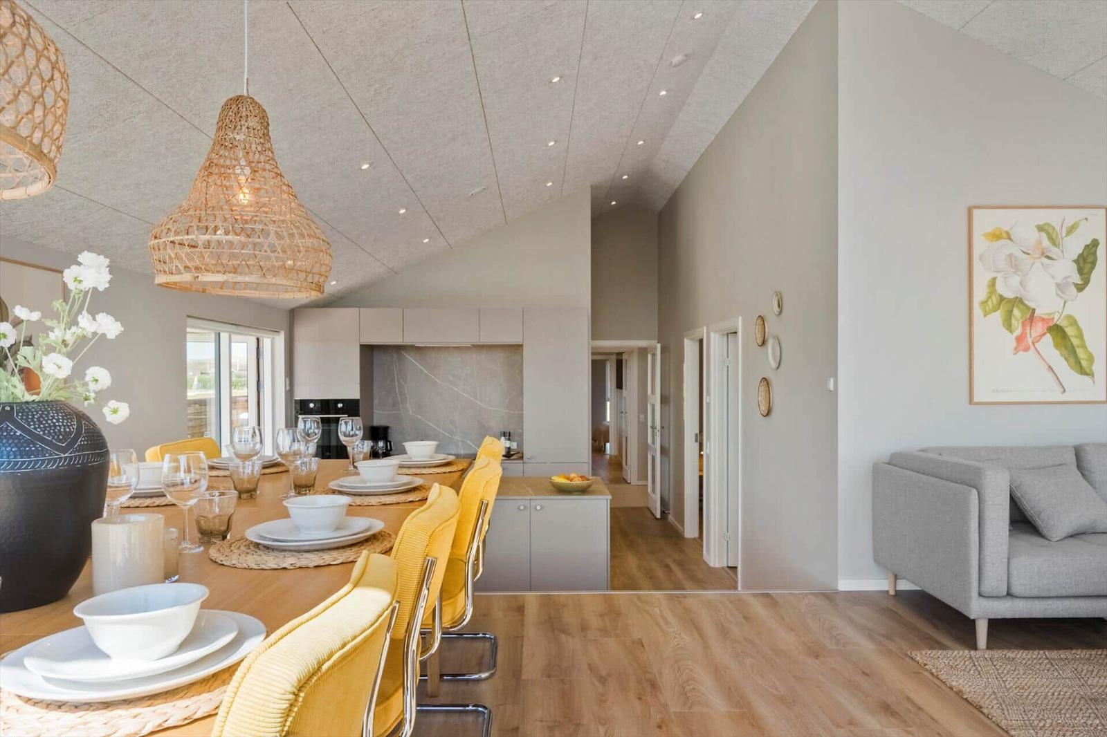 Esszimmer mit gelben Stühlen und Wohnbereich mit grauem Sofa.