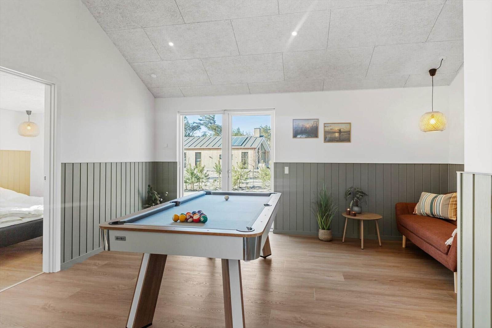 Pooltisch im Wohnbereich mit Sitzgelegenheit und Blick auf die Außenanlage.