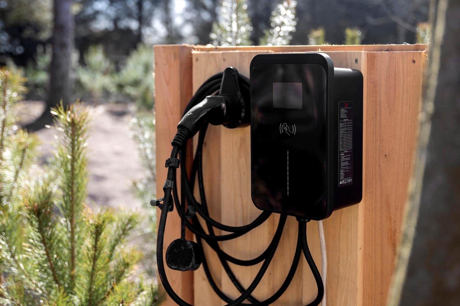 Elektrische Ladestation an Holzwand im Wald
