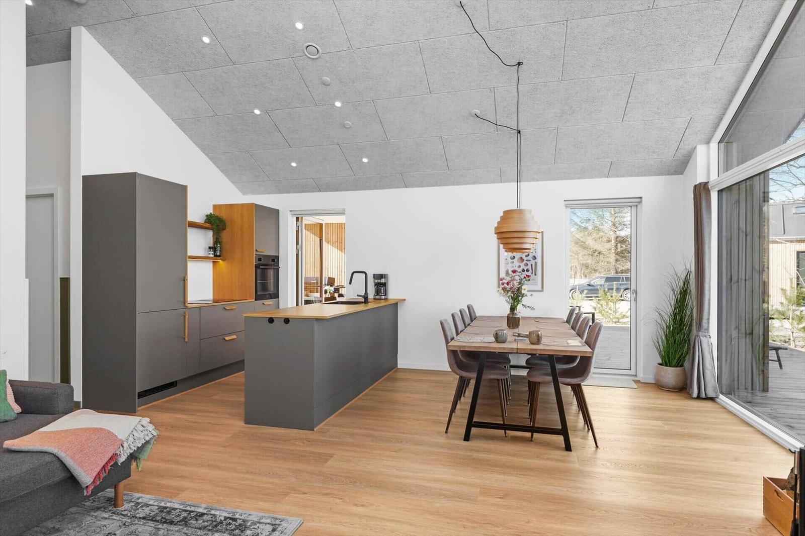 Moderne Küche mit Essbereich und Holzboden. Große Fenster und Deckenleuchte.