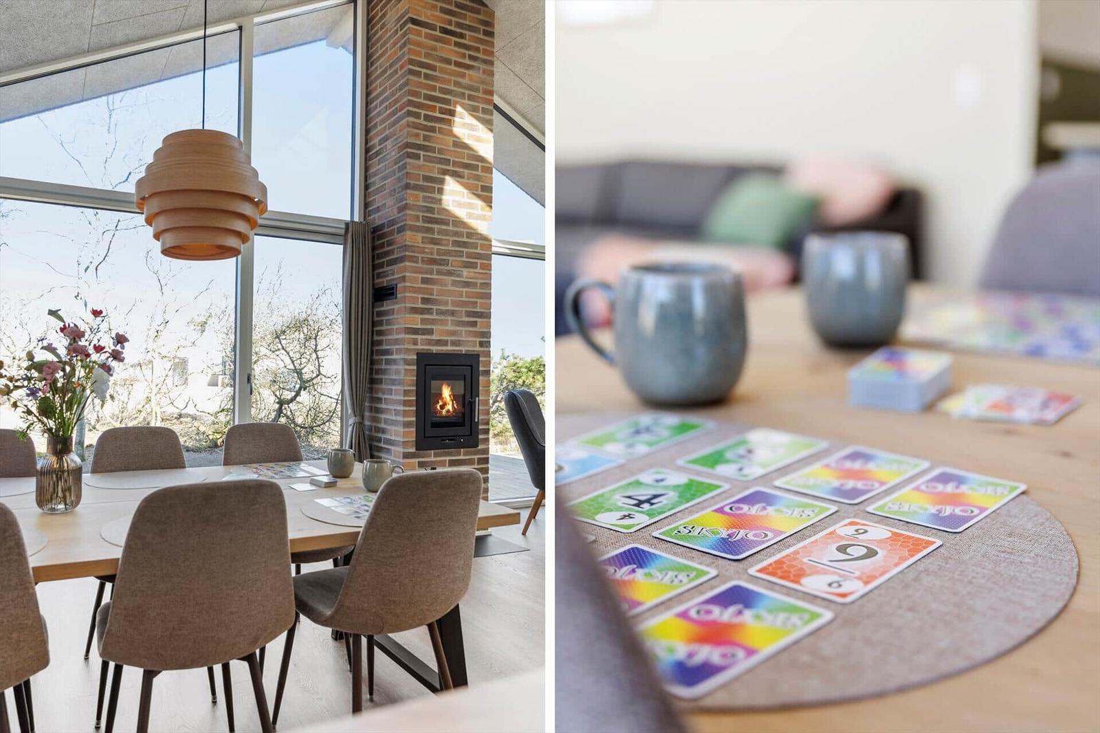 Esszimmer mit Holztisch, Stühlen und Kamin. Spielkarten und Tassen auf Tisch.